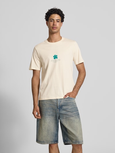 Männermodel trägt Regular Fit T-Shirt mit Logo-Print Modell 'Eres' von Jack & Jones in Creme, reine Baumwolle, Rundhalsausschnitt, Ganzkörperansicht von vorne.