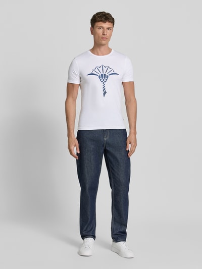 Männermodel trägt T-Shirt mit Rundhalsausschnitt Modell 'Alerio' von JOOP! Collection, reine Baumwolle, weiß mit Logo, Ganzkörperansicht von vorne.