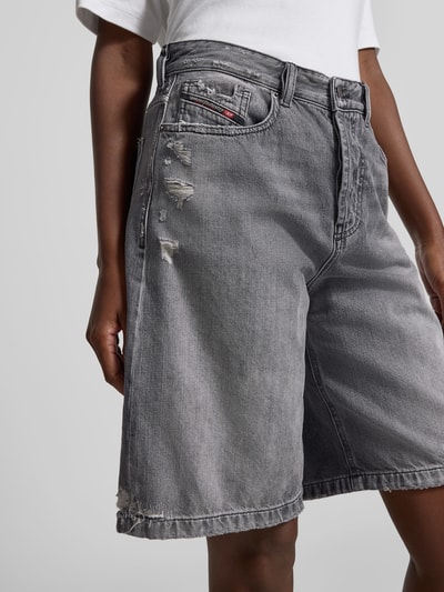 Kobieta prezentuje Relaxed Fit Jeansshorts aus Baumwolle od Diesel, szare, bawełna, krój relaxed fit, destroyed-look, 5 kieszeni, zapięcie na guzik i zamek, długość nogawki 25 cm, szerokość w rozmiarze 27: 40 cm; zbliżenie na górną część ciała i szorty