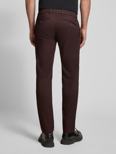 Männermodel trägt Slim Fit Chino aus Baumwoll-Mix von bugatti in Dunkelbraun, Gesäßtaschen, Ganzkörperansicht Rückansicht.