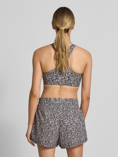 Frauenmodel trägt Freesoft Sport-BH mit Racerback Modell 'selma' von VARLEY aus Material-Mix mit Stretch-Anteil und rückseitigem Logo-Print, Ganzkörperansicht Rückansicht.