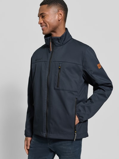 Männermodel trägt Jacke mit Reißverschlusstaschen von camel active in Dunkelblau mit Label-Patch, Statement-Stitching, Ganzkörperansicht von vorne.