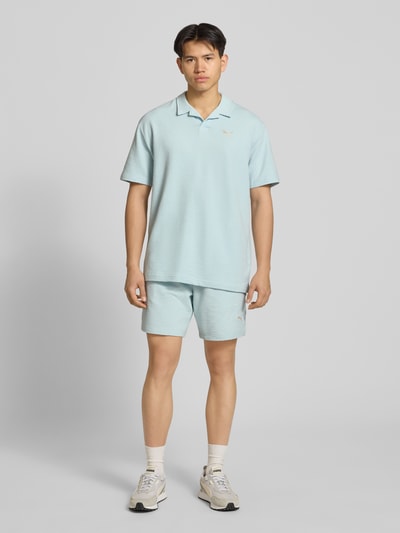 Männermodel trägt Regular Fit T-Shirt mit Logo-Stitching von PUMA PERFORMANCE aus Baumwoll-Mix mit Stretch-Anteil, Strukturmuster, Ganzkörperansicht von vorne.