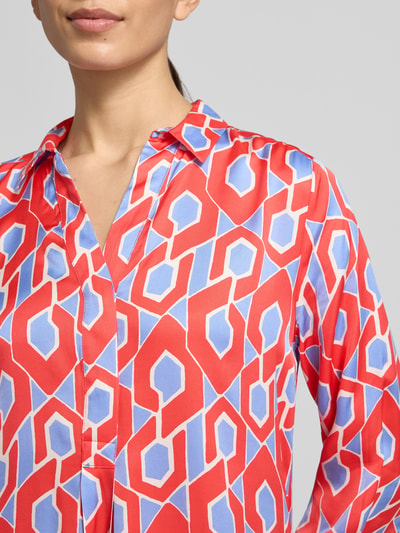 Frauenmodel trägt Knielanges Hemdblusenkleid mit V-Ausschnitt von Milano Italy aus reiner Viskose, buntes geometrisches Muster, Nahaufnahme Oberkörper.