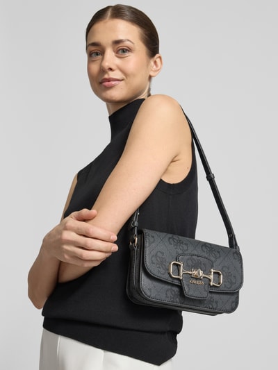 Vrouwenmodel draagt Umhängetasche met Label-Detail Modell 'JANIE' van Guess, zwart, verstelbare schouderriem, textuur, hoofvak met drukknoopsluiting, binnenvak met rits, breedte 21 cm, lengte 14 cm, diepte 5 cm, lengte schouderriem 78 cm, close-up bovenlichaam vooraanzicht.