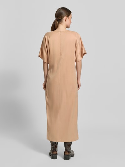 Frauenmodel trägt Midikleid mit Knotendetail Modell 'INDAH' von Drykorn aus Cupro-Baumwoll-Mix, Gerader-Schnitt, Rückenlänge 127 cm, Ganzkörperansicht Rückansicht.
