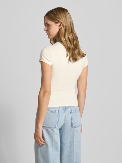 Frauenmodel trägt T-Shirt mit Motiv-Stitching und Rundhalsausschnitt von REVIEW aus Baumwoll-Elasthan-Mix, Slim-Fit, Rückenlänge 54 cm, Ganzkörperansicht Rückansicht.