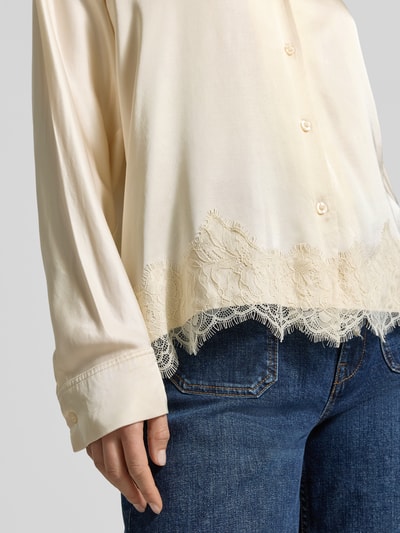 Frauenmodel trägt Relaxed Fit Bluse aus Viskose mit Spitzenbesatz von Jake*s Collection in Creme, Knopfleiste, Jeans kombiniert, Nahaufnahme Oberkörper.