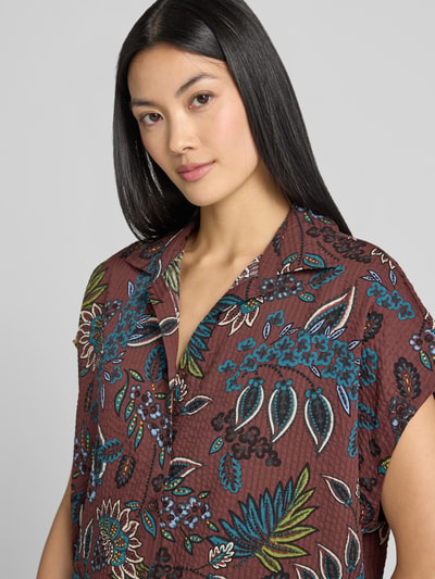 Frauenmodel trägt Relaxed Fit Hemdbluse aus Viskose-Mix von zero mit Allover-Paisley-Print, Hemdblusenkragen, kurzärmelig, bordeauxfarben mit bunten Paisley-Mustern, dezente Struktur im Stoff, Damen Hemdbluse im Baumwoll-Viskose-Mix, Nahaufnahme Oberkörper.