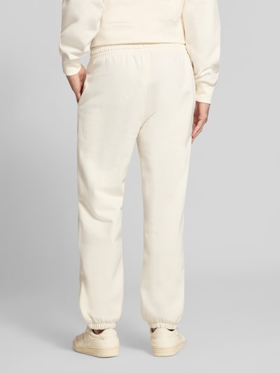 Männermodel trägt Sweatpants mit Label-Detail von Champion in Beige, Baumwollmischung, gerader Schnitt, Ganzkörperansicht Rückansicht.
