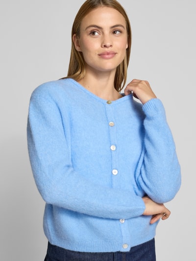 Frauenmodel trägt Strickjacke mit Knopfleiste Modell 'VITOW' von American Vintage in Hellblau, Alpaka-Lanawoll-Mix, gerippte Abschlüsse, lockerer Schnitt, Nahaufnahme Oberkörper
