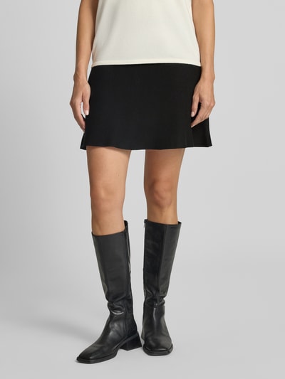 Frauenmodel trägt ausgestellten Mini-Rock aus Viskose-Baumwoll-Mix Modell 'ELLY' von VERO MODA, unifarben schwarz, Feinstrick, Nahaufnahme Unterkörper.