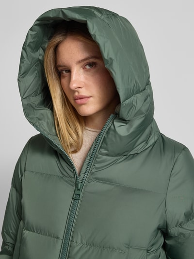 Frauenmodel trägt Regular Fit Daunenjacke mit Label-Patch von Marc O'Polo in mattem Grün, sichtbare Stepp-Struktur, Nahaufnahme Oberkörper. Damen Daunenjacke von Marc O'Polo.