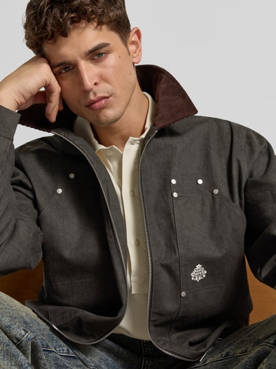 Männermodel trägt Jacke aus reiner Baumwolle von Don’t Waste Culture in Dunkelgrau mit Kontrastkragen, Zweiwege-Reißverschluss, Nahaufnahme Oberkörper. Rückenlänge 68 cm, Schulterbreite 53 cm, Ärmellänge 68 cm, gerade Passform, sichtbare Eingrifftaschen