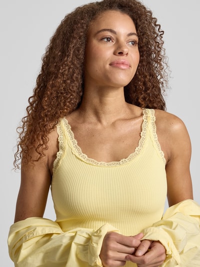 Frauenmodel trägt Slim Fit Tank Top aus Bio-Baumwoll-Mix Modell 'SARA' von Only in Unifarbe Gelb, Feinripp mit Spitzendetails, Nahaufnahme Oberkörper.
