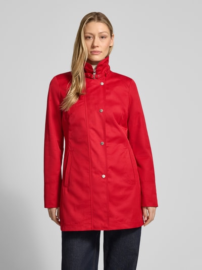 Frauenmodel trägt Trenchcoat mit Stehkragen und Eingrifftaschen von Fuchs Schmitt in Rot, Baumwoll-Mix, taillierter Schnitt, Nahaufnahme Oberkörper.