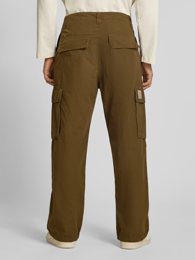 Mężczyznamodel nosi spodnie cargo z bawełny Model 'Columbia' od Carhartt Work In Progress, odcień brązowy, krój regular fit, widoczne kieszenie cargo, kieszenie z tyłu, zakończenia nogawek z regulacją, szerokość w rozmiarze 32: 43 cm, długość wewnętrzna nogawki w rozmiarze 32: 76 cm, widok całej sylwetki z tyłu.