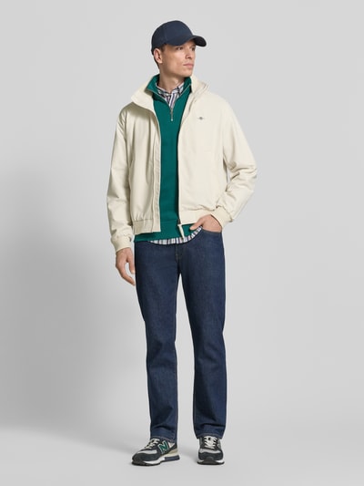 Männermodel trägt Jacke mit Stehkragen und Zweiwege-Reißverschluss von Gant, Material-Mix mit Baumwoll-Anteil, Regular-Fit, Stehkragen, Zweiwege-Reißverschluss, Eingrifftaschen, Label-Stitching, dezentes Beige mit Kontrast, Rückenlänge 67 cm, Schulterbreite 49 cm, Brustweite 62 cm, Ärmellänge 69 cm, Ganzkörperansicht von vorne.