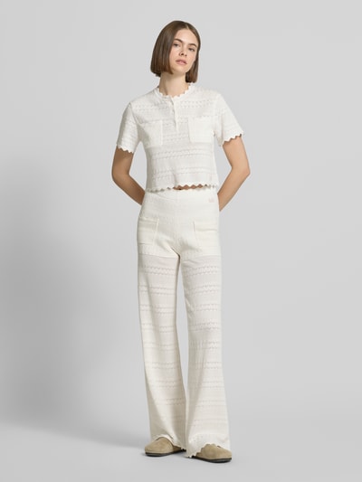 Frauenmodel trägt Strickhose mit Eingrifftaschen Modell 'Aurea' von OH APRIL aus cremefarbenem Baumwoll-Mix mit Flared Fit, Ganzkörperansicht von vorne.