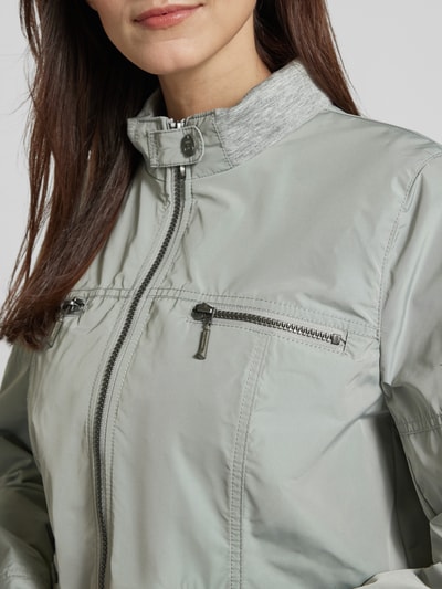 Kobieta nosi Jacke mit Zweiwege-Reißverschluss od Amber & June, kolor jasnozielony, stójka, krój regular fit, zbliżenie na górę sylwetki