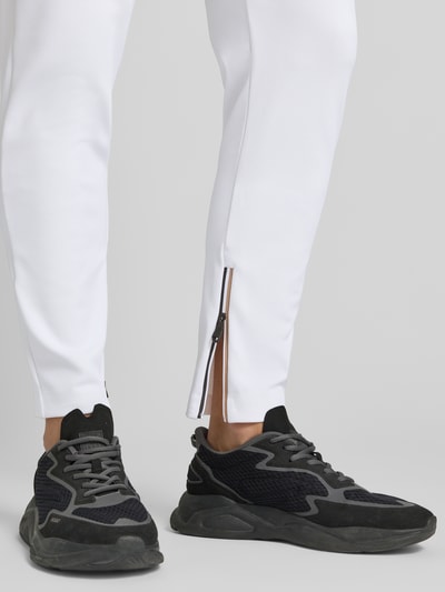 Männermodel trägt Regular Fit Sweatpants mit Label Stitching Modell 'JT_TOC SPIN LONG' von BOSS Green, weiß, Kontraststreifen, Nahaufnahme Beine.