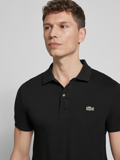 Męski model trägt Slim Fit Poloshirt aus reiner Baumwolle von Lacoste, efekt: jednolity kolor, wyhaftowane logo, kołnierzyk polo, krótki rękaw, prążkowane zakończenie rękawów, wykończenie z rozcięciami po bokach, wykończenie materiału: pika, materiał: bawełna; nahaufnahme oberkörper.