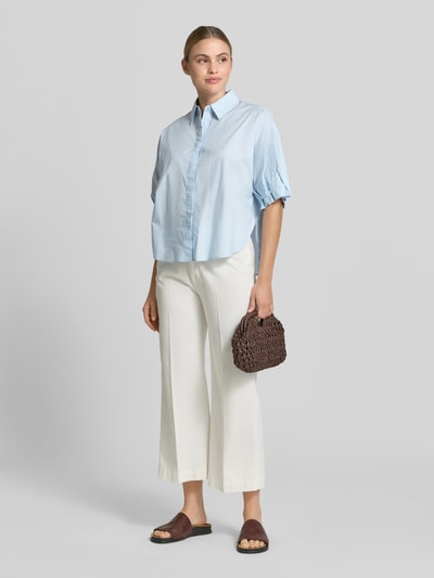 Frauenmodel trägt Relaxed Fit Bluse mit verdeckter Knopfleiste Modell 'Finoa' von OPUS, reine Baumwolle, hellblau, Ganzkörperansicht von vorne.