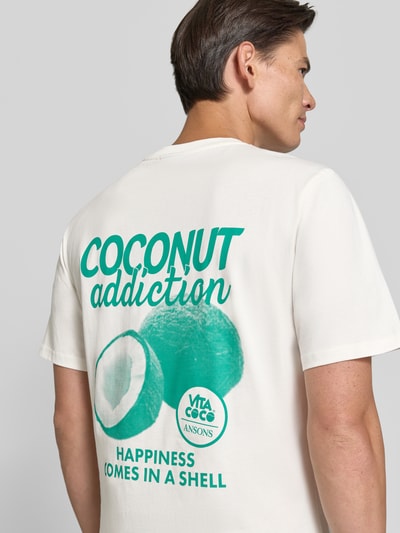 Männermodel trägt Relaxed Fit T-Shirt aus reiner Baumwolle von REVIEW x ANSON’S, weiß mit grünem Motiv-Print, Rückenlänge 68 cm, Ganzkörperansicht Rückansicht.