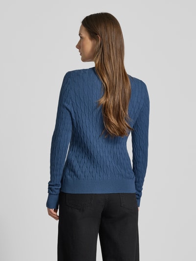 Frauenmodel trägt Regular Fit Strickjacke mit Viskose-Anteil Modell 'FANTASTIC' von Vero Moda in Blau mit Zopfmuster, Rückenansicht.