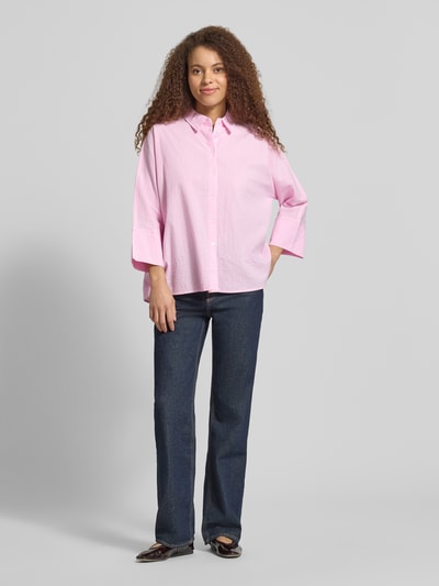 Frauenmodel trägt Boxy Fit Bluse aus reiner Baumwolle Modell 'AUGUSTA' von Only mit Allover-Muster, Hemdkragen, gestreift, einreihige Knopfleiste, Kimonoärmel, Twillgewebe, Farbton Rosa, Ganzkörperansicht von vorne.