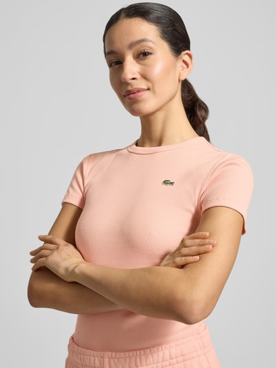Vrouwenmodel draagt Slim Fit T-shirt uit puur katoen van Lacoste Sport, look: effen, logostitching, ronde hals, korte mouw, rib. Nahaufnahme Oberkörper.