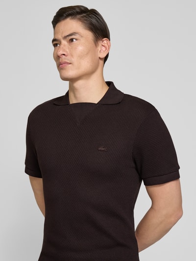Männermodel trägt Regular Fit Poloshirt aus reiner Baumwolle von Lacoste, Farbe Dunkelbraun, Optik: Unifarben, Struktur, Nahaufnahme Oberkörper.