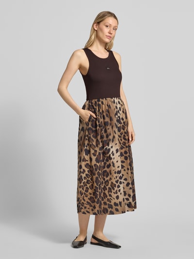 Frauenmodel trägt Midikleid mit Eingrifftaschen von Smith and Soul aus elastischem Baumwoll-Modal-Mix mit taillierter Passform und Rundhalsausschnitt, zweifarbig in Braun und Schwarz mit Animalprint-Struktur, Ganzkörperansicht von vorne.