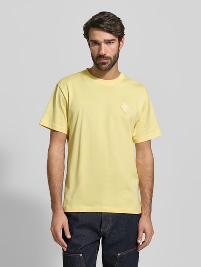 Męski model nosi Regular Fit T-Shirt aus reiner Baumwolle Modell 'JERSEY LOURD' od Lacoste, jasnożółty, logo, krótki rękaw, bawełna, całkowity widok z przodu.