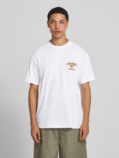 Männermodel trägt Regular Fit T-Shirt mit Motiv-Print auf der Rückseite von Carhartt Work In Progress, weiße Reine Baumwolle, Rundhalsausschnitt, Label-Detail, Ganzkörperansicht von vorne, Rückenlänge bei Größe M: 73 cm.