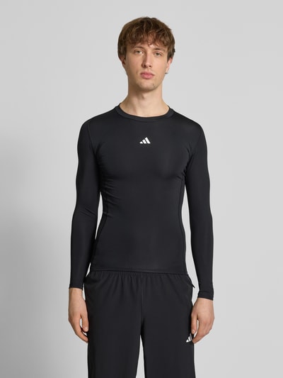 Mannenmodel draagt Shirt met lange mouwen met labelprint van adidas Training, materiaalmix met stretch, slim fit, zwarte kleur, ronde hals, ruglengte maat M 65 cm, vooraanzicht volledige lichaamsopname.