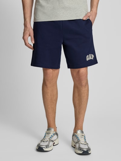 Männermodel trägt Sweatshorts mit elastischem Bund von GAP in Dunkelblau, Baumwoll-Mix, Relaxed-Fit, Logo, Nahaufnahme Oberschenkel-Ansicht.