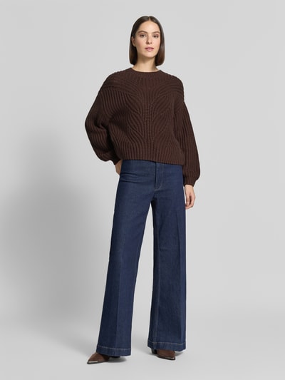 Frauenmodel trägt Relaxed Fit Strickpullover aus Baumwoll-Mix von Apricot, dunkelbraun, Rundhalsausschnitt, gerippte Abschlüsse, kombiniert mit blauer Jeans, Damen Strickpullover, Ganzkörperansicht von vorne.