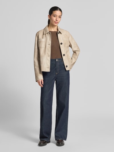 Frauenmodel trägt Regular Fit Jacke in Leder-Optik von Amber & June in Beige, mit Umlegekragen, Brusttaschen, durchgehender Knopfleiste, kombiniert zu dunkler Jeans und braunem Top, strukturierte Oberfläche, Ganzkörperansicht von vorne, Rückenlänge 54 cm, Schulterbreite 42 cm, Brustweite 52 cm, Ärmellänge 63 cm.