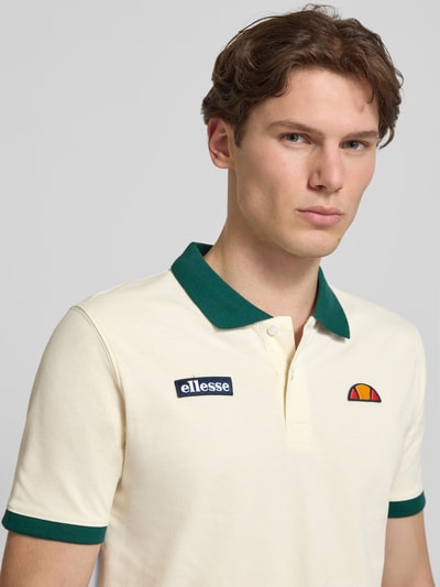 Männermodel trägt Regular Fit Poloshirt mit Label-Stitchings von ellesse aus Reine Baumwolle, beige mit grünem Kragen, Nahaufnahme Oberkörper. Rückenlänge bei Größe M: 77 cm, Knopfleiste, Herren.