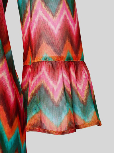 Detailaufnahme Frauenmodel trägt Oversized Tunika mit V-Ausschnitt Modell 'ACELO' von Banana Moon, materiał z domieszką stretchu, wzór w kolorowe zygzaki, rękaw z falbaną, tunika damska, schnürverschluss.