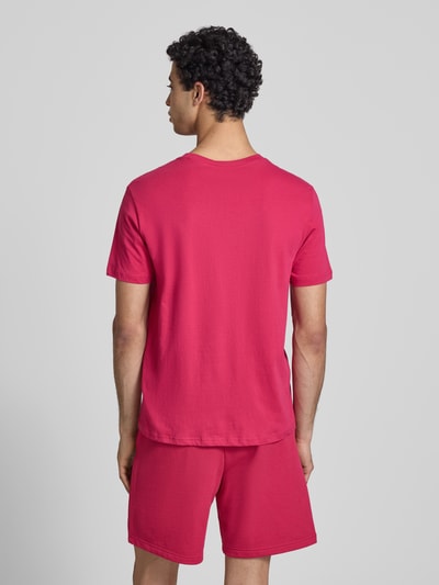 Männermodel trägt T-Shirt mit Label-Print und Rundhalsausschnitt von CHAMPION in Pink, reine Baumwolle, Regular Fit, Ganzkörperansicht Rückansicht.