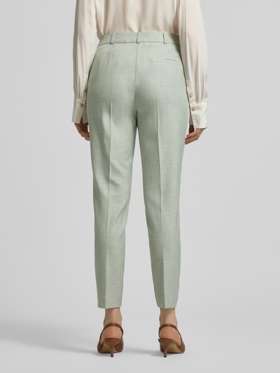 Vrouwenmodel draagt Slim Fit Stoffhose aus Viskose-Mix mit Bügelfalten van comma in lichtgroen met gestreken vouwen en achterzak, elastische viscosemix, haak- en ritssluiting, taillewijdte 38 cm, binnenbeenlengte 72 cm, volledige achterkantansicht.