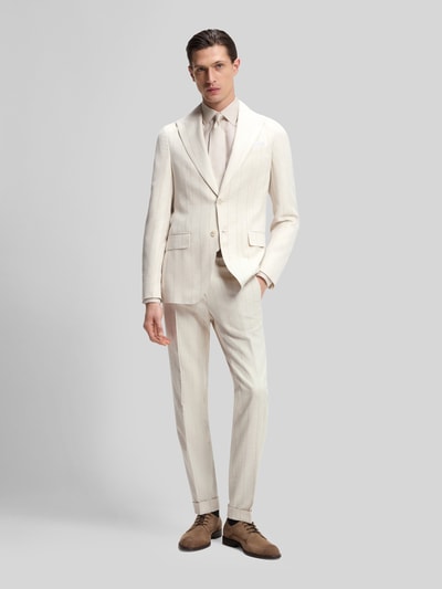 Männermodel trägt Slim Fit Anzug aus Baumwoll-Woll-Mix Modell 'H-HUGE-2PCS-261' von BOSS in Beige mit Allover-Muster und Streifen, Ganzkörperansicht von vorne.