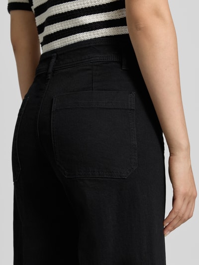 Frauenmodel trägt schwarze Wide Fit Jeans aus Baumwoll-Mix Modell 'JESSIE' von MANGO mit aufgesetzten Taschen, Nahaufnahme Rückansicht.