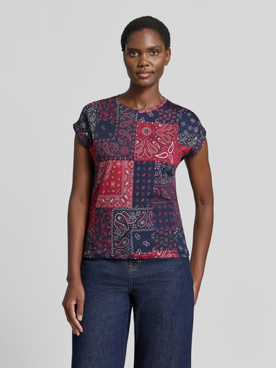 Kobiece model prezentuje Damski t-shirt z bawełny o kroju taliowanym, okrągły dekolt, rękawy z podwinięciem, t-shirt z Christian Berg Woman, długość tyłu w rozmiarze S: 55 cm, kolorowy wzór, zdjęcie całej sylwetki od przodu.