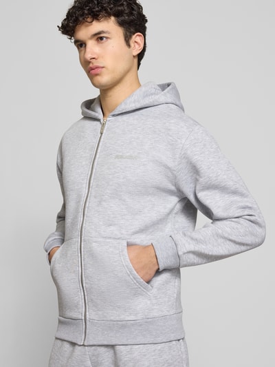 Männermodel trägt Sweatjacke mit Känguru-Tasche von REVIEW in Grau, Baumwoll-Mix, Relaxed-Fit, Reißverschluss, Nahaufnahme Oberkörper.