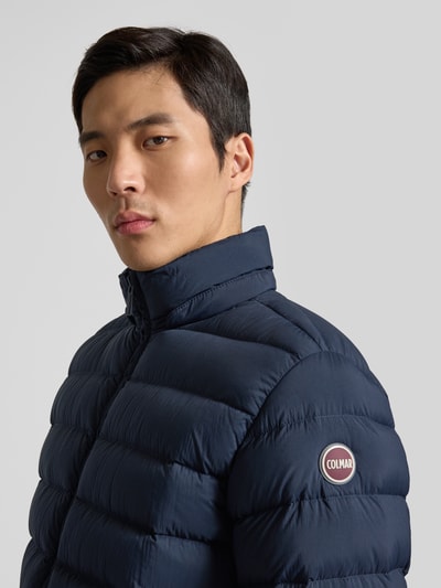 Męski model nosi granatową Steppjacke mit Kapuze od Colmar Originals, widoczna faktura pikowania, zbliżenie na górną część ciała.