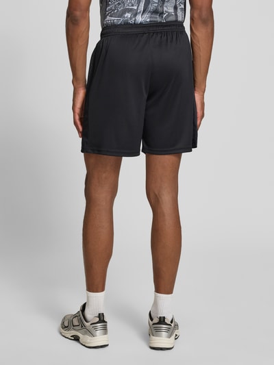Männermodel trägt Relaxed Fit Shorts mit Logo-Print von COLUCCI, elastischer Bund, Motiv-Stitching, schwarze Farbe, Ganzkörperansicht Rückansicht.