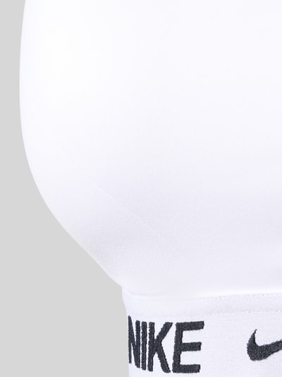 Frauenmodel trägt weißes Bustier mit Label-Details, verstellbaren Trägern von NIKE TRAINING, Material-Mix, Nahaufnahme Oberkörper.
